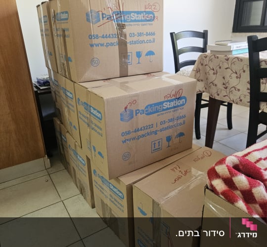 קופסאות קרטון לאריזה בחדר עם שולחן וכיסאות